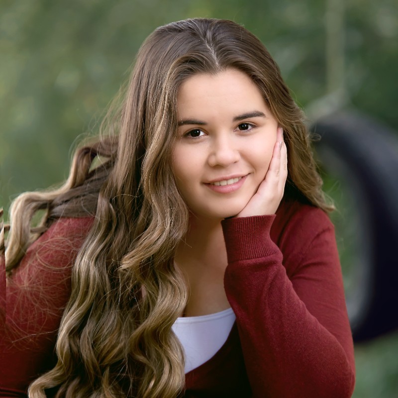 Portrait of Shayla in front of a green background.